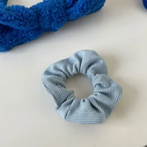 Close-up showing the ribbed fabric texture of the light blue scrunchie hair accessory
