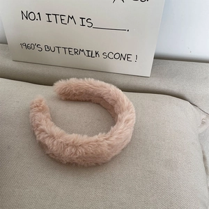 Close-up of soft pink faux rabbit fur headband with fluffy texture on beige fabric