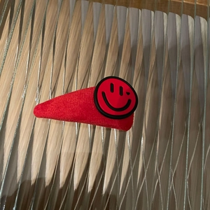 Nahaufnahme der roten Plüsch-Haarklammer mit einem schwarzen Smiley-Muster auf Stoff