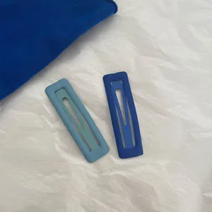 Detail of blue matte rectangular snap hair clips on textured white background