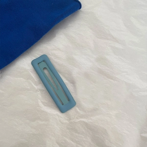 Minimalist light blue matte rectangular hair clip on textured white paper background