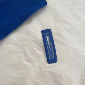 Macro view of rectangular Klein blue matte metal BB hair clip on textured paper
