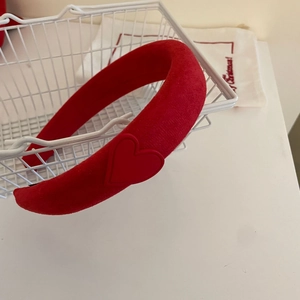 Detailaufnahme von rotem gepolstertem Samtstirnband mit Herz-Patch auf Korb