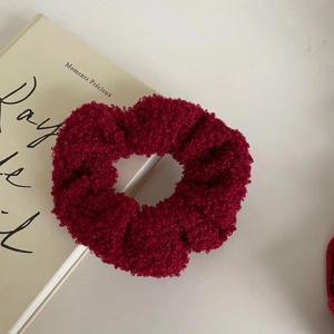Detail of a plush burgundy velvet scrunchie placed on an elegant French book background