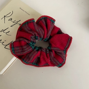 Macro shot of red and green plaid scrunchie with soft velvet texture and fine stitching