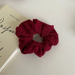 Detailed close-up of wine red knitted scrunchie texture on an elegant book prop
