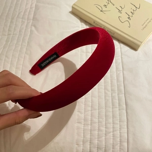 Elegant red velvet padded headband with handmade label on white quilted background