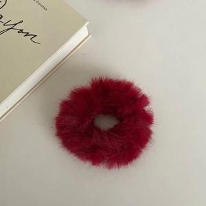 Elegant wine red plush scrunchie on a minimalist cream desk with a French book backdrop