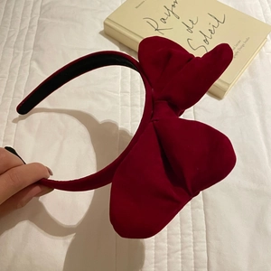 Detail view of a large red velvet bow headband held over a book for a cozy French look