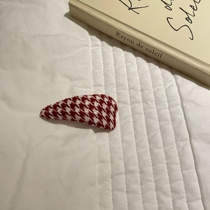 Detail of red and white houndstooth fabric hair clip on elegant white background