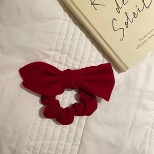 Detailed view of elegant red velvet bow scrunchie on a white quilted background