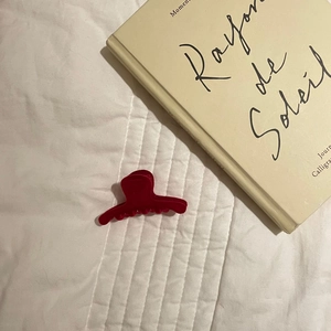 Detail shot of a dark red flocked claw clip on white quilted fabric with a book