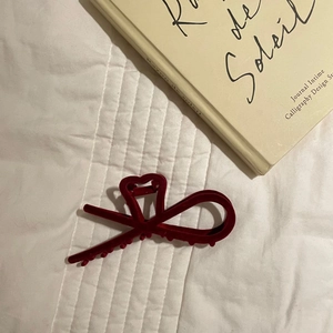Detail of a deep red flocked hair claw clip on quilted fabric with a French book backdrop