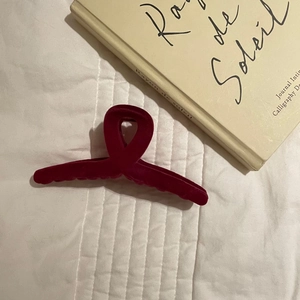 Detail of elegant wine red flocked hair claw clip on soft quilted white background