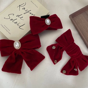 Elegant red velvet bow hair clips with pearls and rhinestones on a vintage background