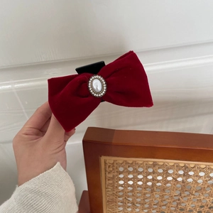 Macro detail of wine red velvet bow hair claw with pearl and rhinestone embellishments