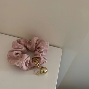 Coletero rosa con flores y cadena dorada con colgante para un peinado chic