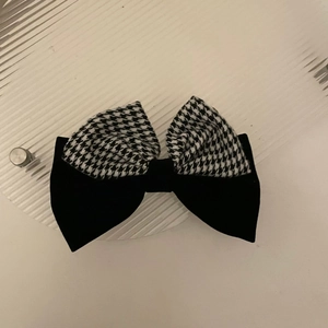 Detail of layered houndstooth and black velvet bow hair clip with elegant pearl accents