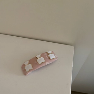 Detalle del pasador de tela rosa con tres bonitos ositos de esmalte blanco y borde dorado