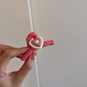 Primer plano detallado de la textura tejida rosa y la decoración de corazón en la pinza