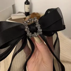 Close-up of black satin bow hair clip with luxury rhinestone buckle and mesh details