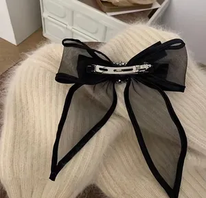 Detail of a large black mesh bow hair clip with rhinestones on a knitted background