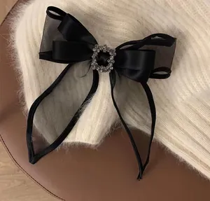 Detail of a large black mesh bow hair clip with a sparkling square rhinestone center