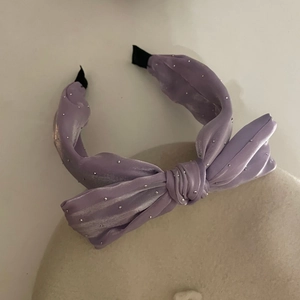Détail du serre-tête nœud violet avec strass scintillants sur tissu satiné