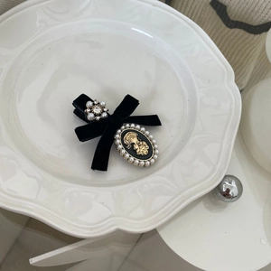 Detail view of French vintage hair clip with black velvet bow and elegant cameo on a white plate