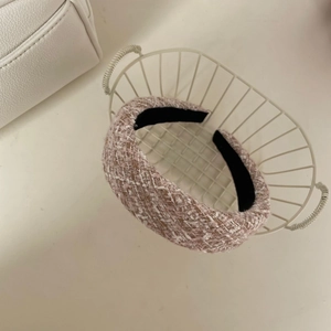 Détails de la texture du serre-tête en tweed rose et blanc dans un panier blanc