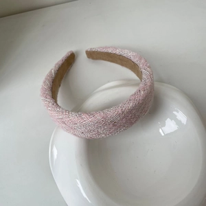 Gros plan d'un serre-tête en tweed rose et blanc sur une assiette blanche en céramique