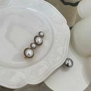 Detail of French vintage gold hair clip featuring four elegant white faux pearls on a tray