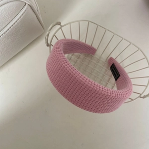 Détail d'un serre-tête en tissu à carreaux rose avec texture épaisse et étiquette tissée
