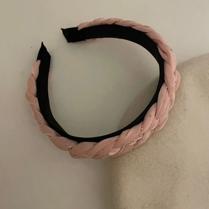 Dettaglio di cerchietto intrecciato in velluto rosa con decorazioni in micro strass lucidi