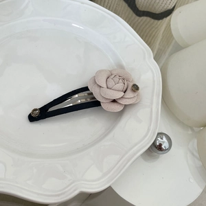 Close-up of a pink fabric camellia hair clip with satin texture and rhinestone accents
