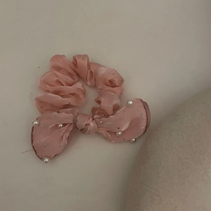 Dettaglio del cerchietto in raso rosa con fiocco, perle bianche e piccoli borchie argento
