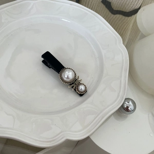 Detailed view of French vintage hair clip with black velvet and faux pearls on a tray