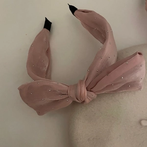Dettaglio del cerchietto in seta rosa con strass luccicanti e punte nere antiscivolo