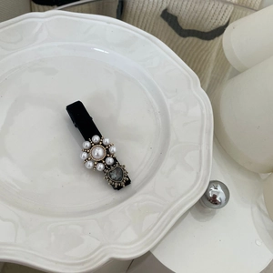 Detail view of velvet hair clip with pearl sunflower and heart rhinestone on ceramic plate