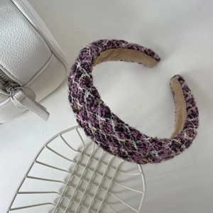 Gros plan d'un serre-tête en tweed violet avec fils dorés et design large rembourré