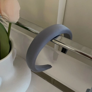 Detail view of a thick blue satin sponge headband displayed on a silver metal stand