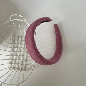 Détail d'un serre-tête large rose poudré avec motif à carreaux texturé et étiquette tissée