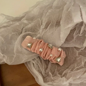 Detail of pink satin hair clip with white pearls and sparkling crystal heart ornaments