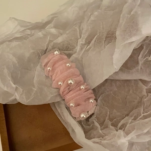 Detail of pink mesh fabric hair clip with white pearls on vintage background