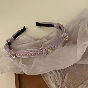 Detail view of purple fabric headband with white pearls and heart-shaped crystal rhinestones