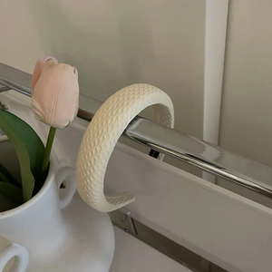 Close-up of cream waffle weave headband with soft sponge padding on a metal rack