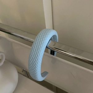 Detailed view of light blue waffle-textured padded headband hanging on a metal stand