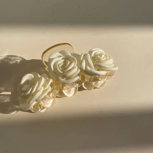 Elegant white fabric camellia hair claw clip with a transparent resin base on cream background