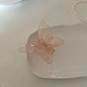 Pince à cheveux papillon rose translucide élégante avec ressort doré dans un plat blanc