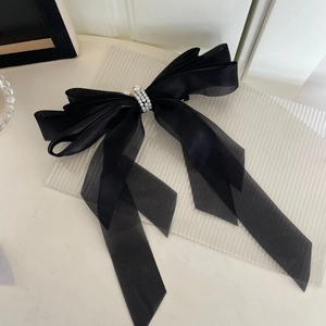 Grande pince à cheveux avec nœud en tulle noir et perles blanches sur socle élégant